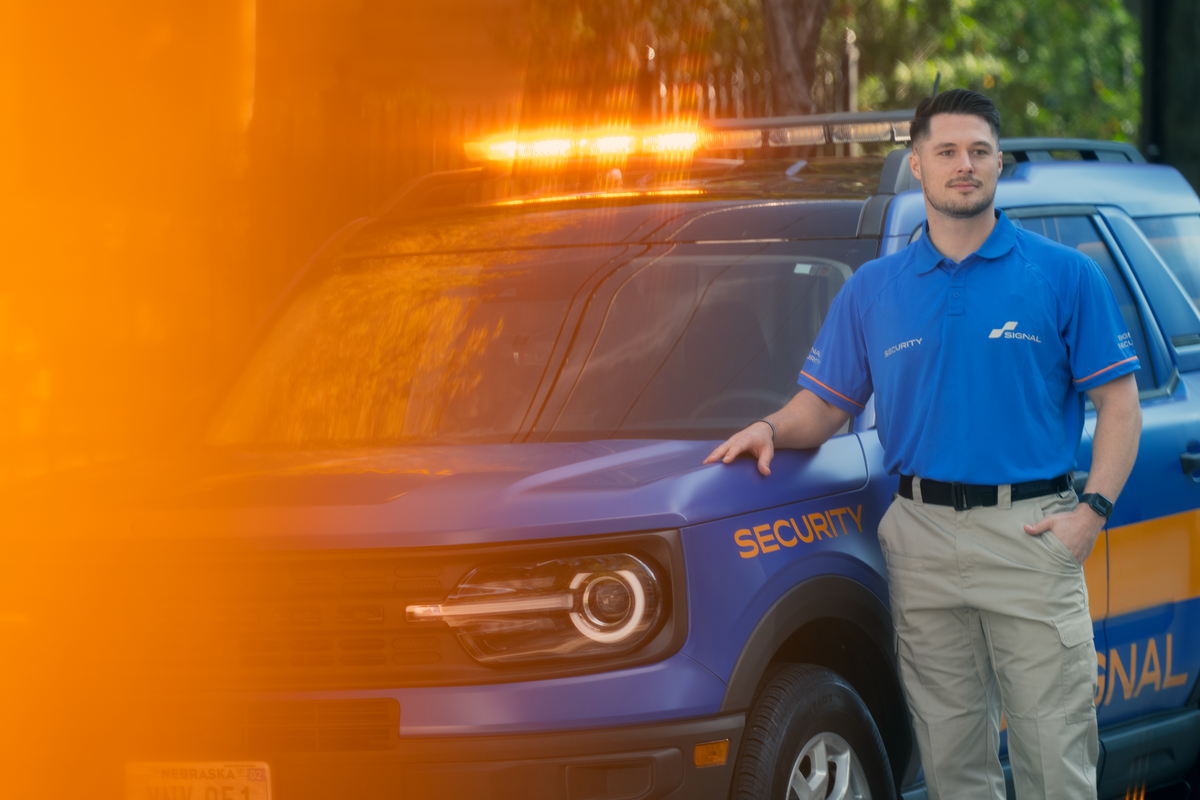 Signal Security officer standing beside a marked patrol vehicle